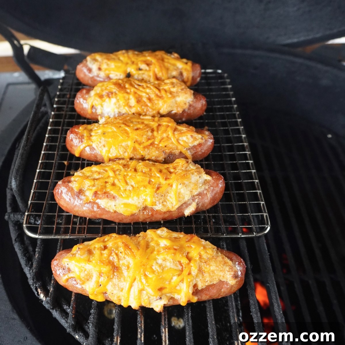 Beautifully grilled sausage popper boats, golden and bubbly with melted cheese, resting on the grates of a hot grill.