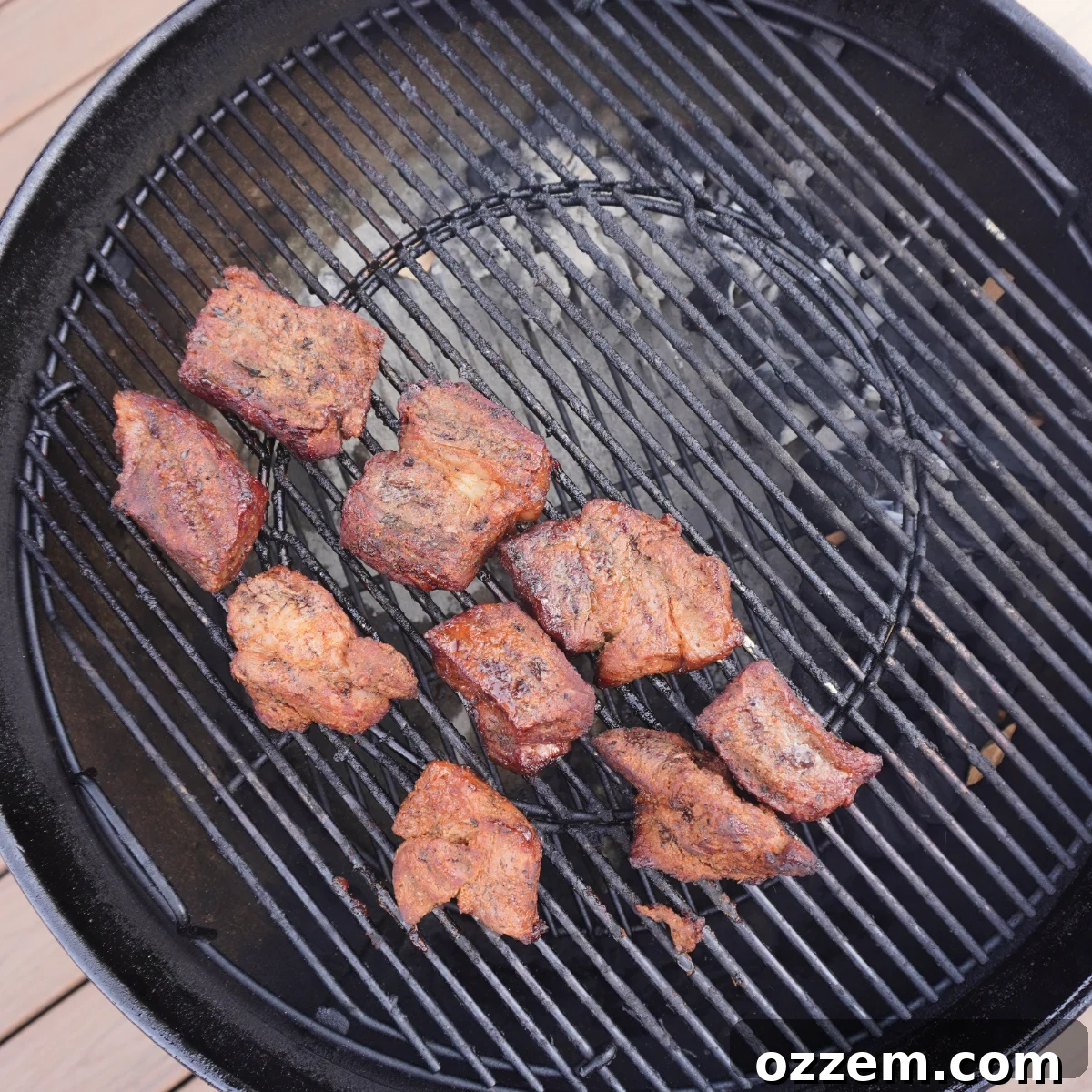 Chuck roast chunks smoking on a grill over indirect heat
