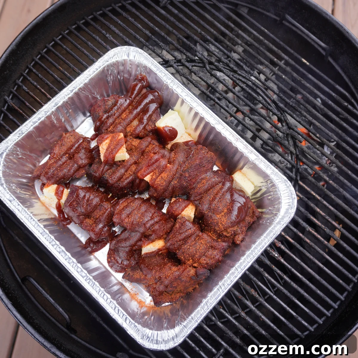 Smoked chuck roast braising in a foil pan with butter and BBQ sauce
