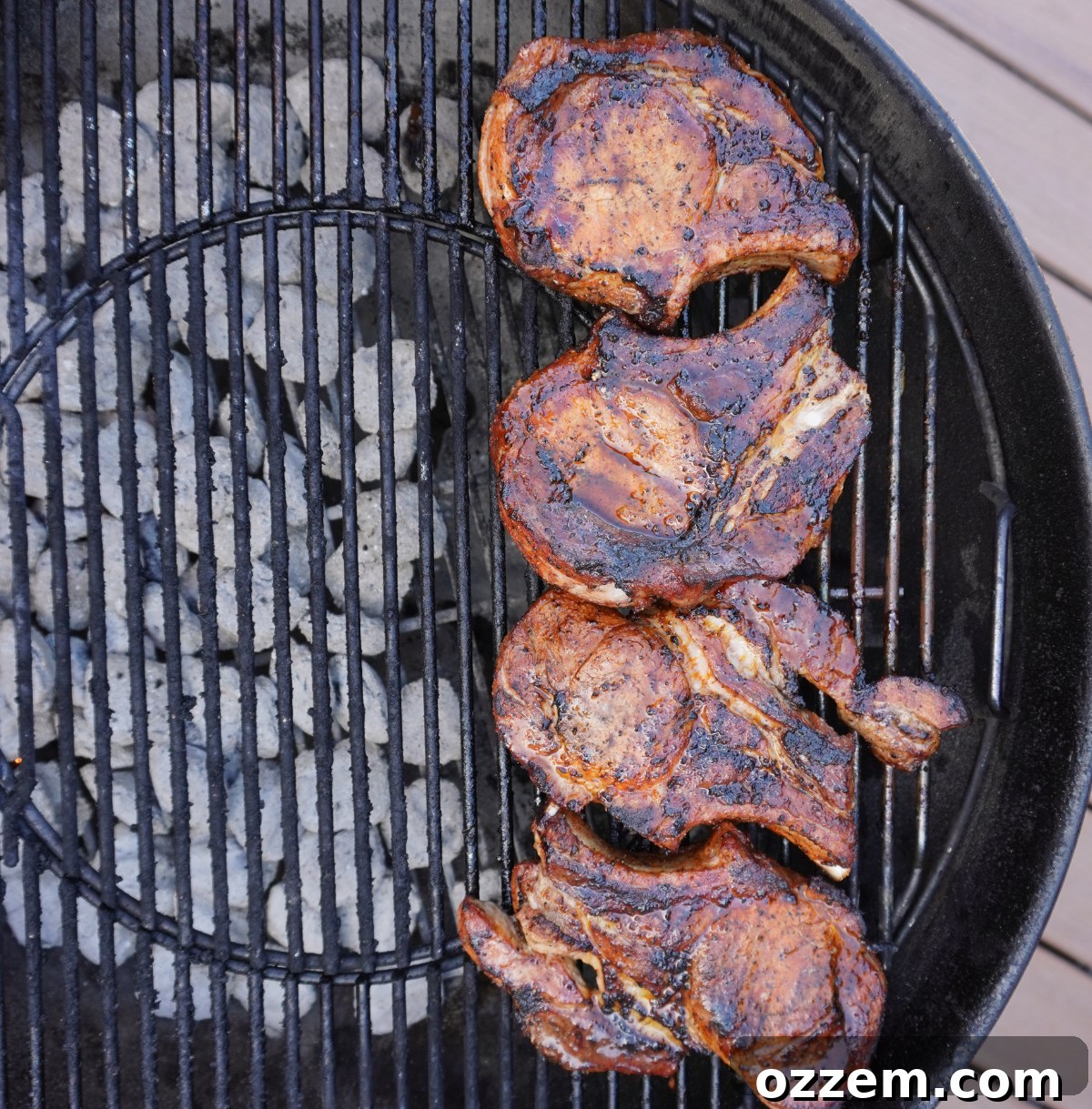 Grilled pork chops cooking on a grill over direct and indirect heat zones.