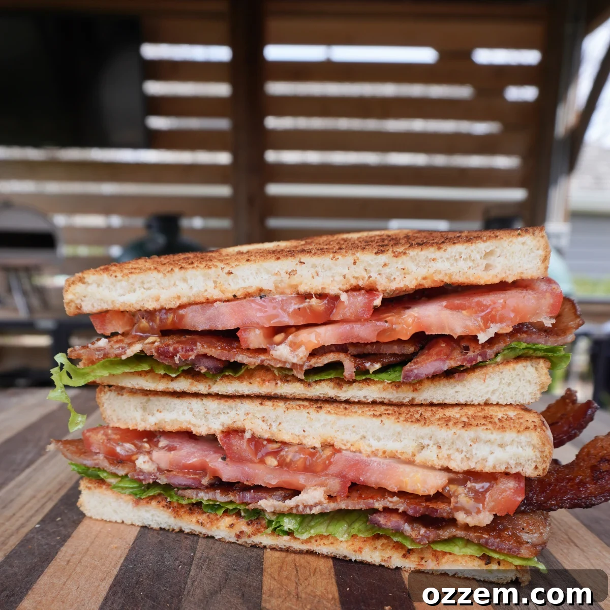 A beautifully assembled Maple Bourbon BLT sandwich, showing crispy bacon, fresh lettuce, and ripe tomato, held together by toasted bread with spicy mayo.