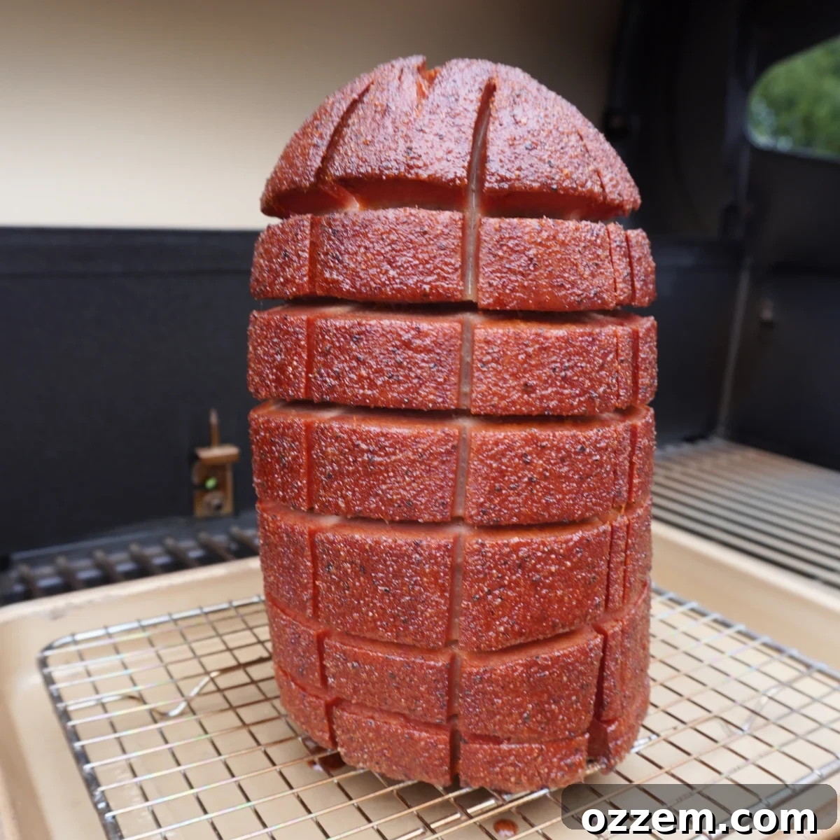 Hearty Smoked Bologna Classic 5 A whole scored and seasoned bologna chub smoking on a grill grate.