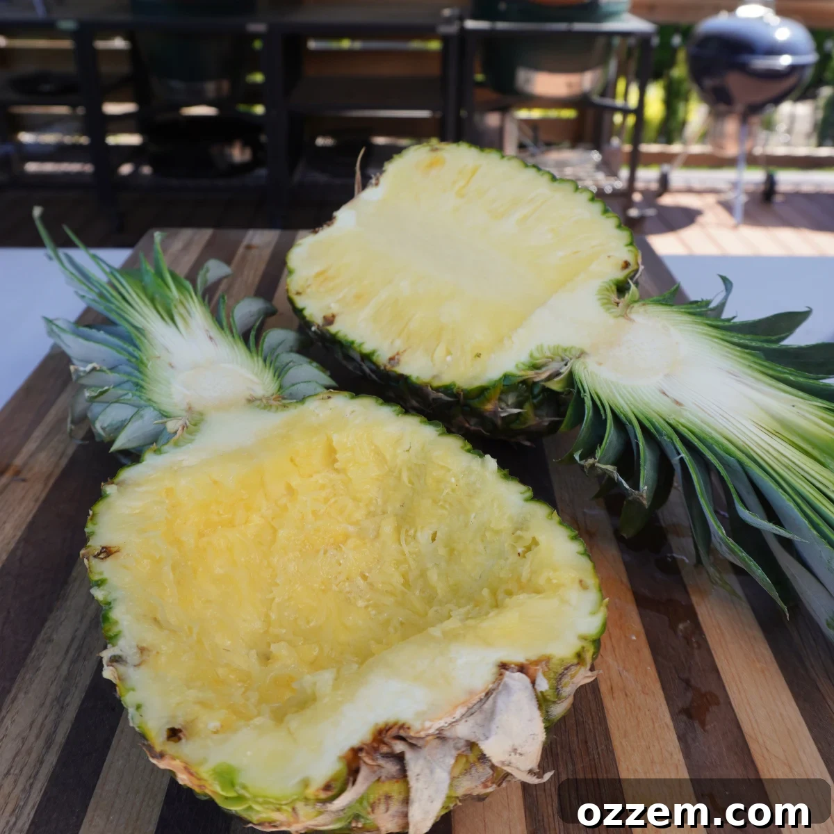 Pineapple halved and scooped out, ready to be filled, with chopped pineapple flesh nearby.