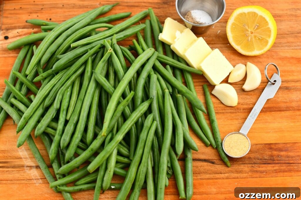 ingredients on a cutting board including green beans, garlic powder, butter, garlic and lemon