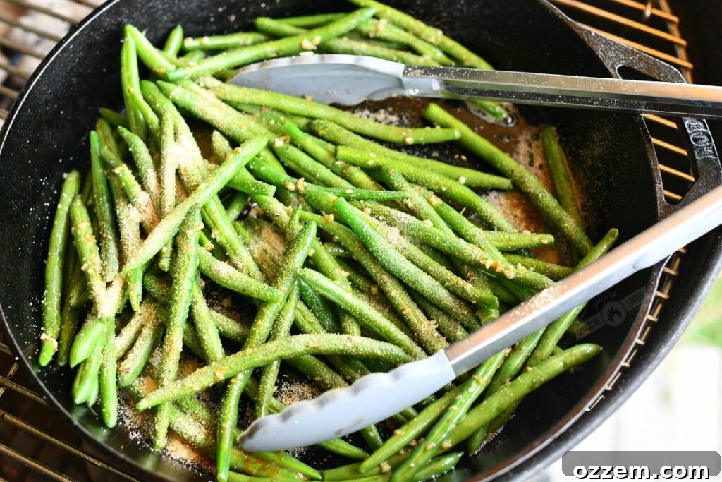 green beans in a skillet topped with seasoning with tongs