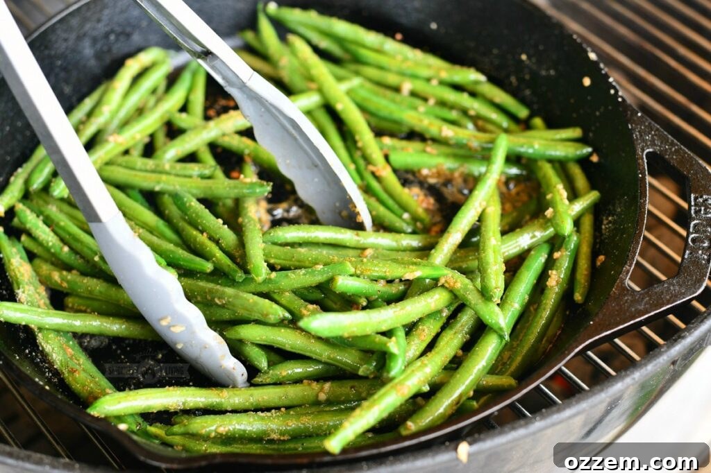 using metal tongs to mix green beans in a skillet