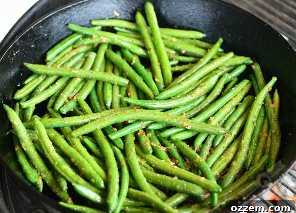 green beans tossed in butter and seasoning in a skillet on the grill