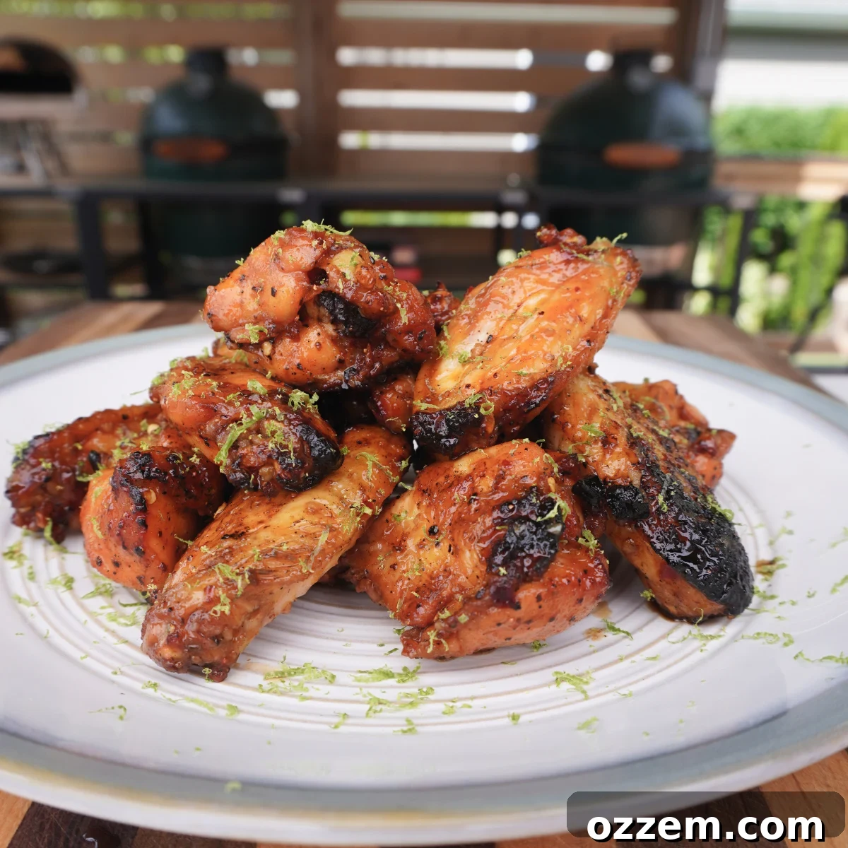 Tower of perfectly grilled Honey Lime Chicken Wings, glistening with sweet and zesty sauce, elegantly plated on a pristine white dish, garnished with fresh lime wedges for a burst of color and aroma.