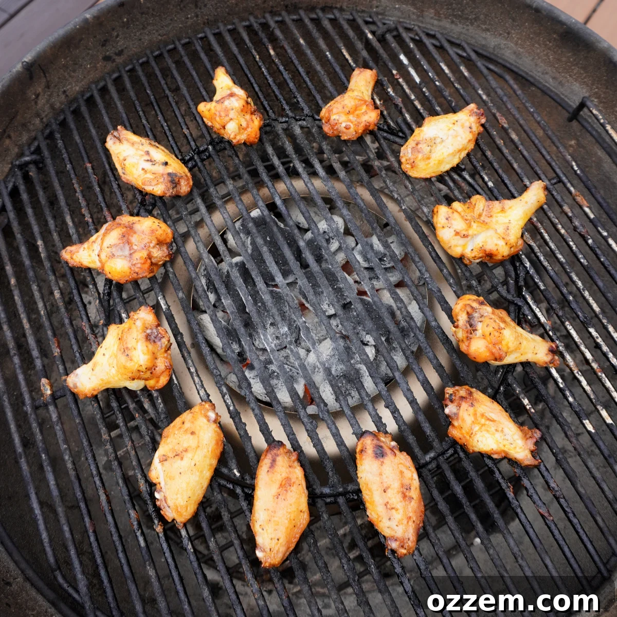 A close-up shot of perfectly grilled honey lime chicken wings, displaying beautiful char marks and a golden-brown hue, arranged directly on the clean grates of a hot grill.
