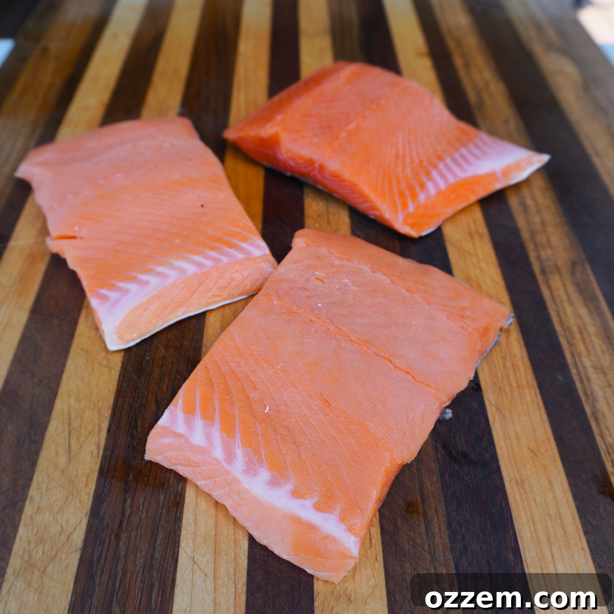 Unseasoned salmon filet on a cutting board, ready for prep