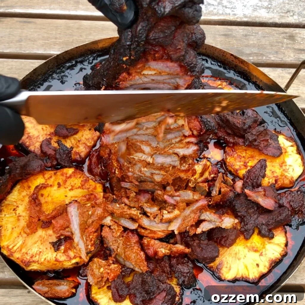 Al Pastor pork being sliced vertically from the trompo onto a cutting board.