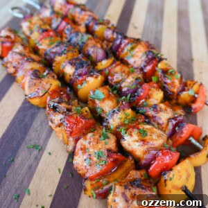 Grilled chicken and vegetable skewers on a white plate with a side of sauce.