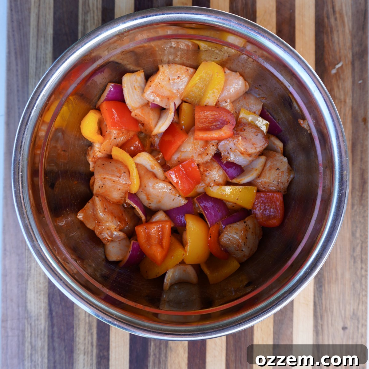 Assorted cubed vegetables including red onion and bell peppers, mixed with chicken for skewers.