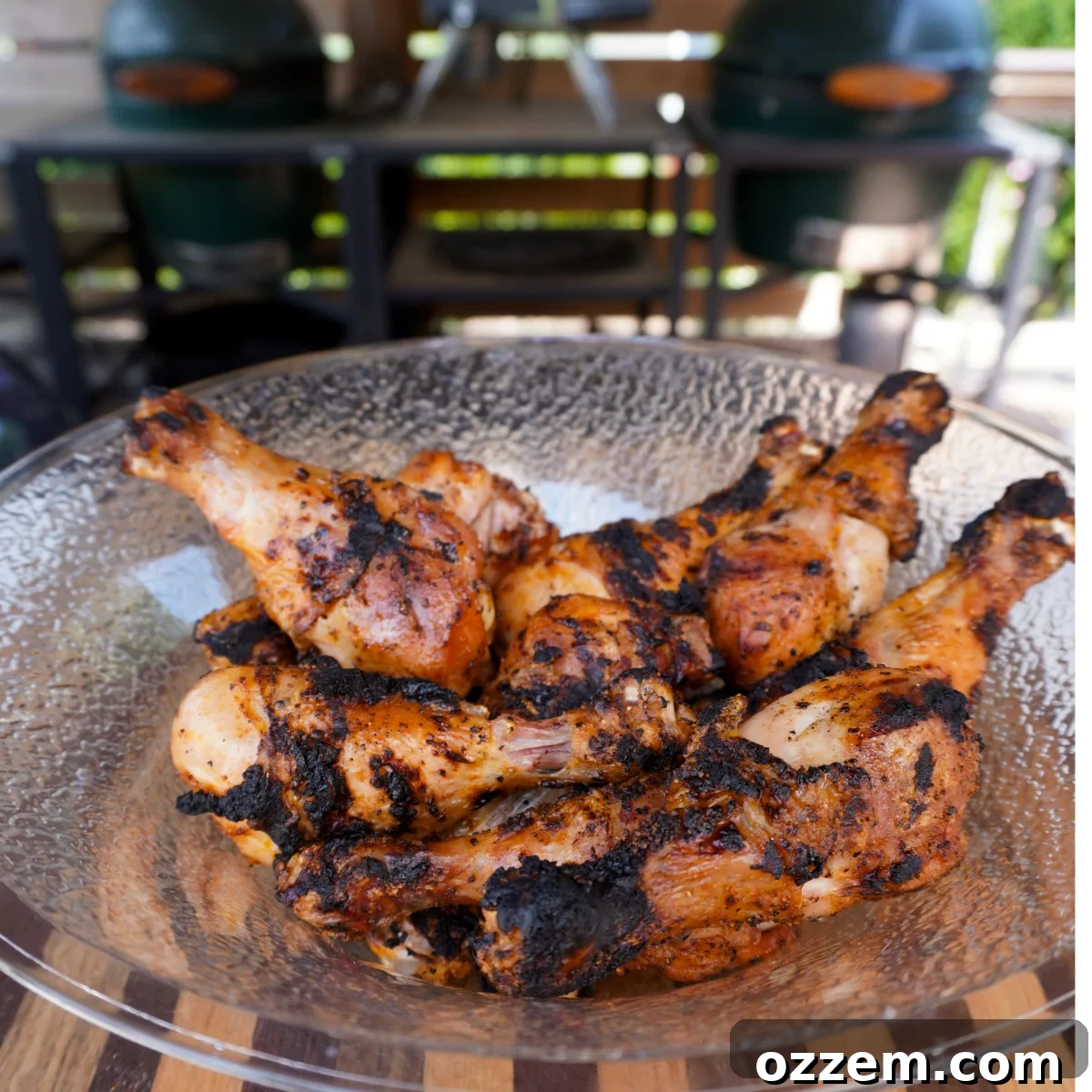 Grilled chicken drumsticks ready to be tossed in Dr. Pepper BBQ sauce on a clear bowl on a wooden cutting board.