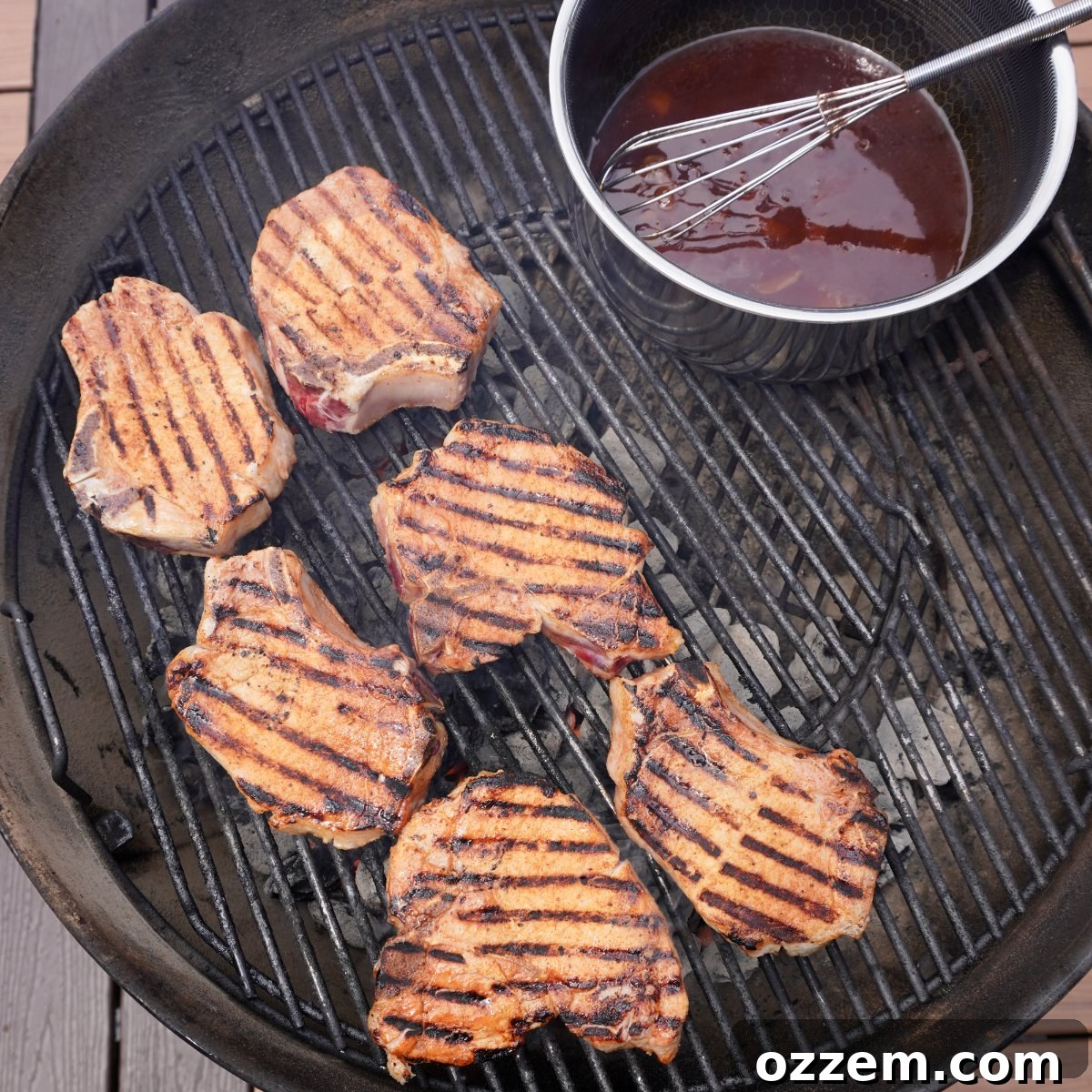 Pork chops searing on a hot grill with visible grill marks.