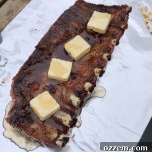 Smoked ribs on foil topped with butter and agave syrup, ready for wrapping