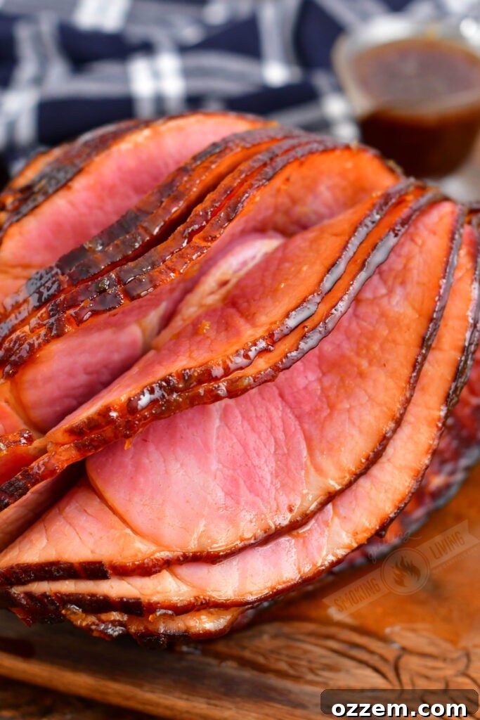 Several glistening slices of smoked ham, coated in a rich glaze, are shown being separated from the main ham, highlighting the beautiful texture and preparation.