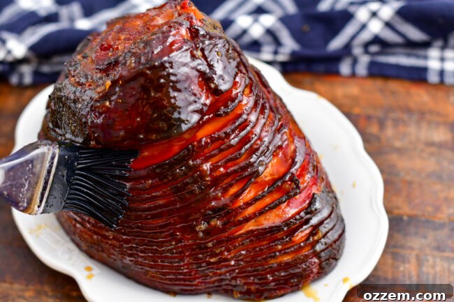 A fully cooked, beautifully glazed smoked ham is presented on a white serving dish, ready to be carved and enjoyed.