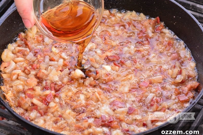 Adding maple syrup to the simmering bacon and onion mixture on the grill