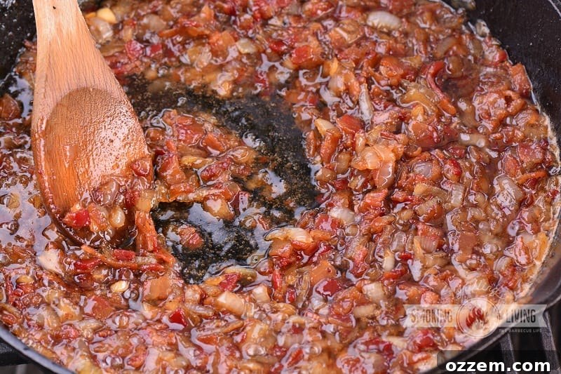 Bacon jam simmering in a cast iron skillet on the grill, infused with smoky flavor