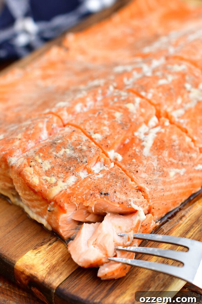 Cutting into a flaky smoked salmon filet with a fork, showing internal texture