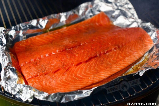 Uncooked salmon fillet on a sheet of foil placed on a smoker grate