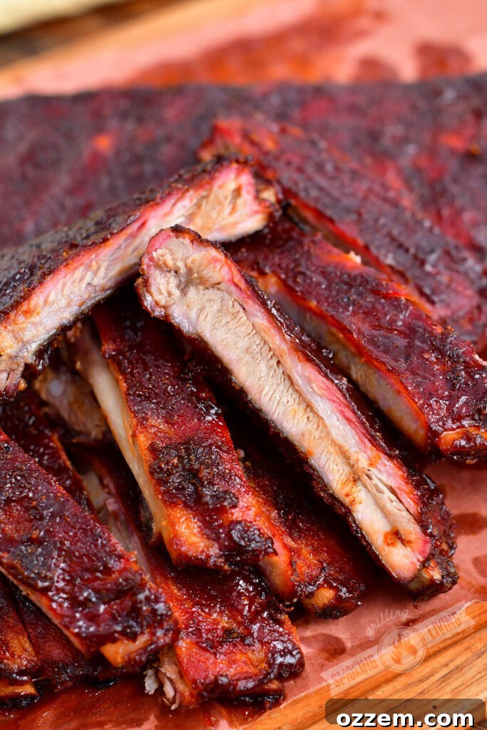 Closer view of individually cut smoked ribs on wood, showcasing their rich color and juicy appearance.