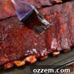 coating cooked St Louis ribs with BBQ sauce using a brush
