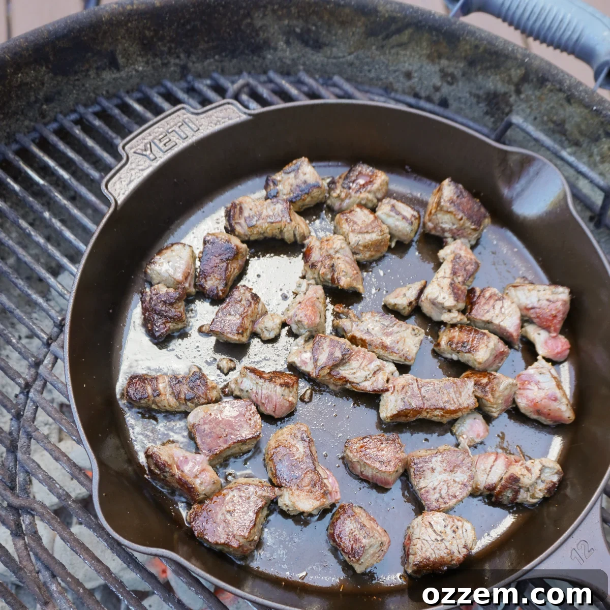 Beautifully grilled and seared beef tips in a cast iron skillet, golden brown and ready for the next step.