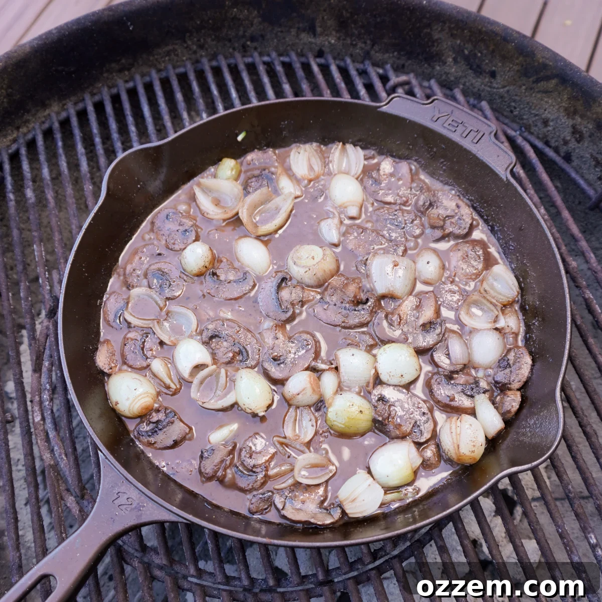 Rich red wine sauce simmering with beef tenderloin tips, mushrooms, and pearl onions, beautifully garnished with fresh herbs.
