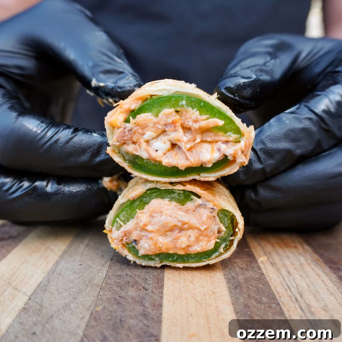 Crispy Jalapeno Popper Lumpia 15 Sliced in half jalapeno popper lumpia showing the crunchy wrapper shell, jalapeno skin, and creamy filling inside.