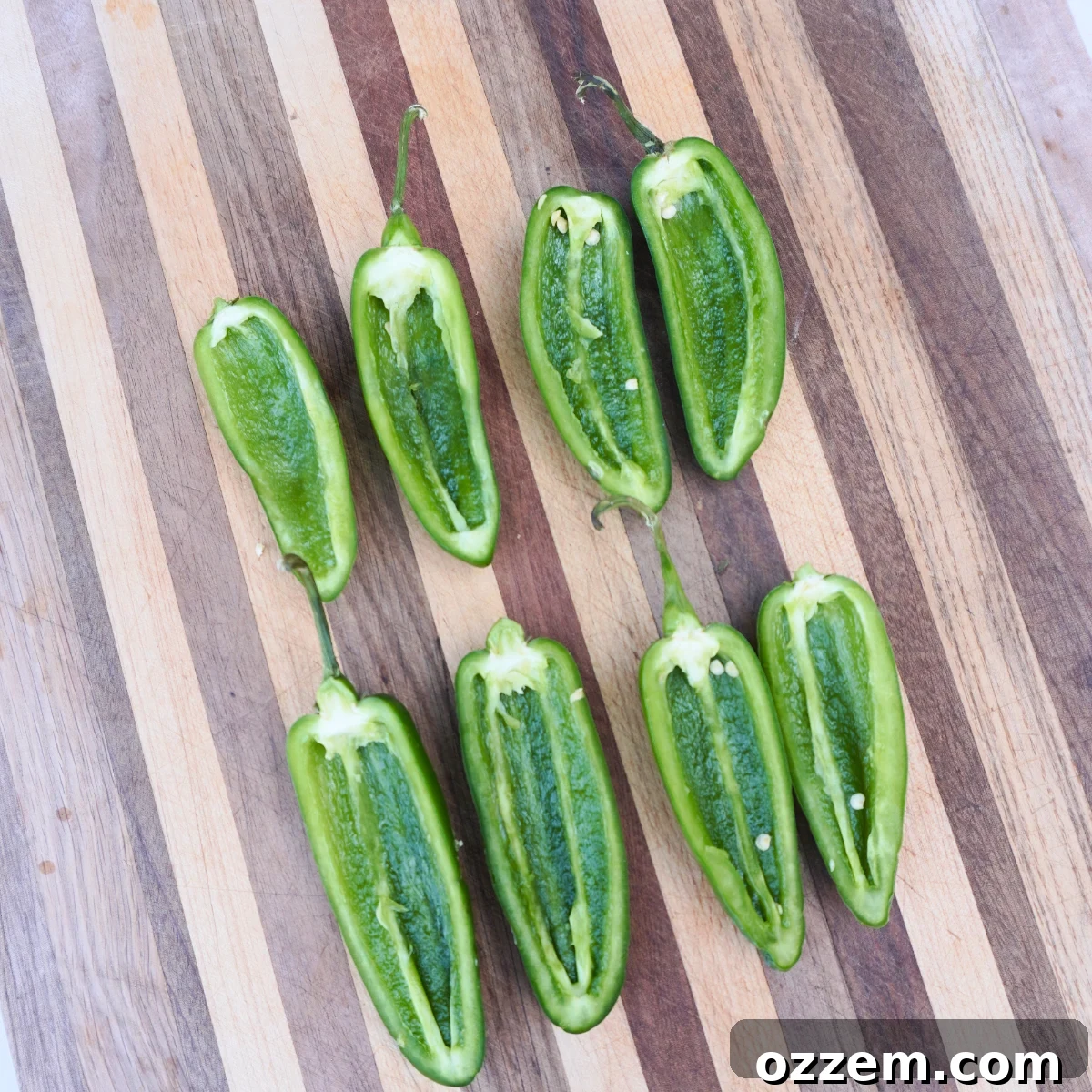 Crispy Jalapeno Popper Lumpia 6 Sliced in half, pitted jalapenos arranged neatly on a cutting board.
