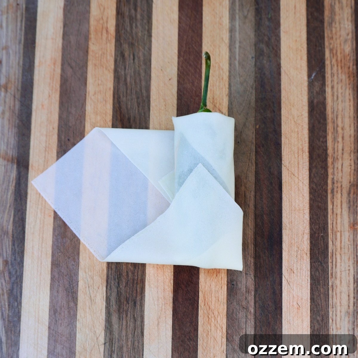 Crispy Jalapeno Popper Lumpia 10 Step-by-step image of folding a lumpia wrapper, showing the side folds over the jalapeno.