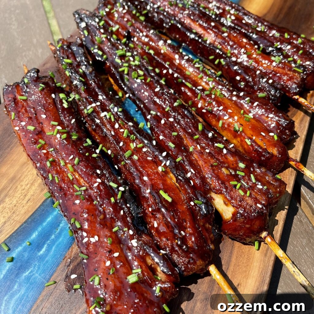 Perfectly grilled Asian style pork belly skewers, glistening with a sticky glaze and sprinkled with sesame seeds.