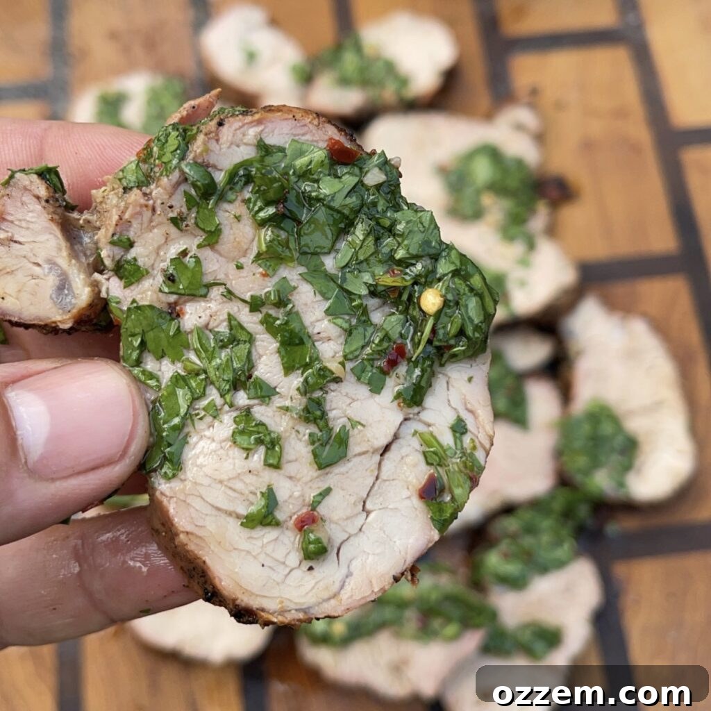 Grilled pork tenderloin slices with a dollop of green chimichurri sauce