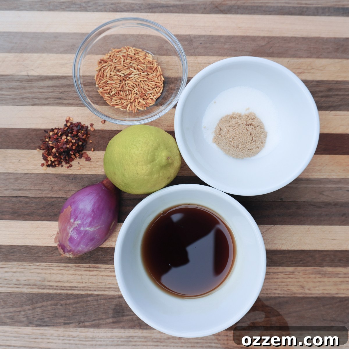 A collection of fresh ingredients laid out for making crying tiger sauce, including herbs, chilies, and sauces.
