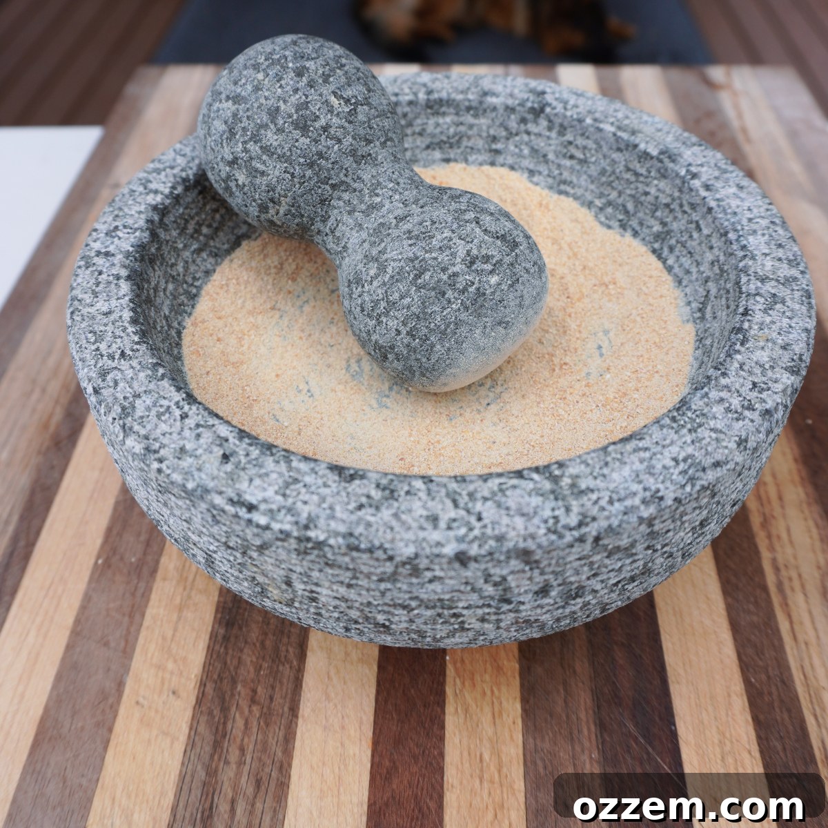 A mortar and pestle with finely ground toasted rice, ready for the next ingredients.