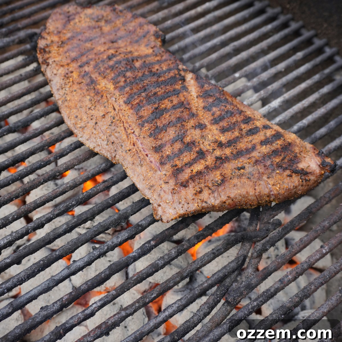 A flat iron steak sizzling beautifully on a hot grill, showing a perfect sear.