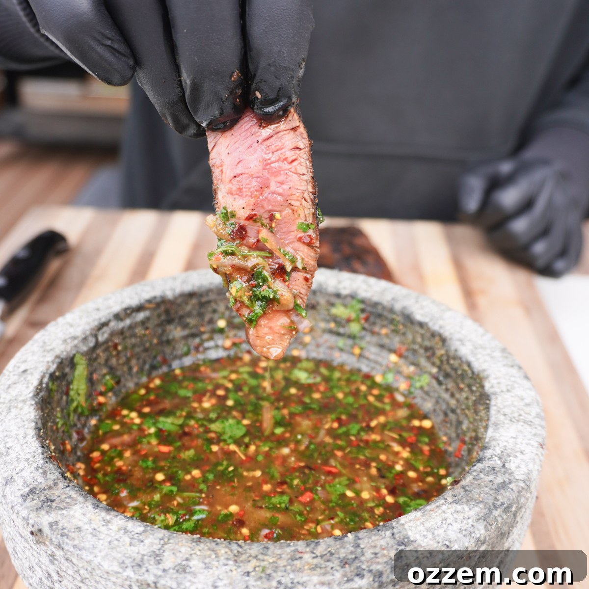 Perfectly sliced flat iron steak, with a piece dipped in the vibrant crying tiger sauce.