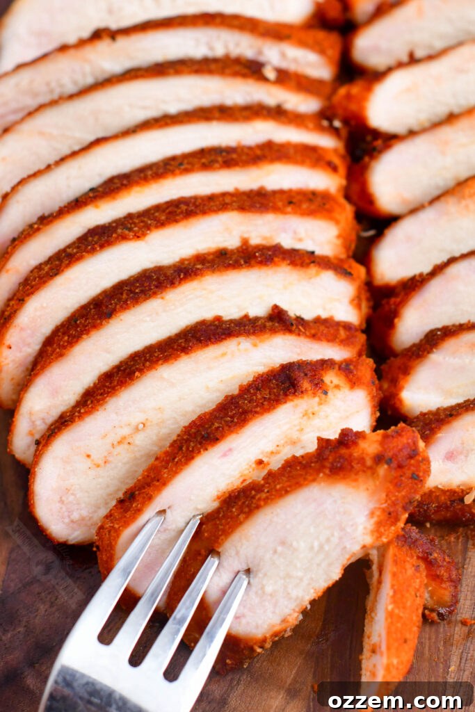 Tender & Smoky Chicken Breast Perfection 3 A fork piercing two juicy slices of smoked chicken breast, highlighting its tender texture