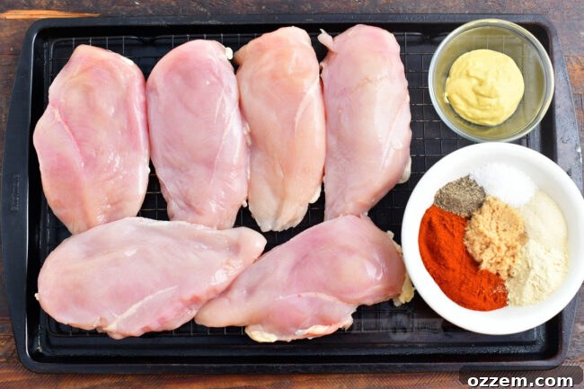 Tender & Smoky Chicken Breast Perfection 4 Raw chicken breasts, Dijon mustard, and homemade seasoning mix arranged on a baking sheet