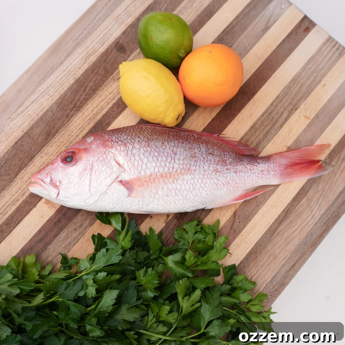 Flame-Kissed Red Snapper 3 Grilled red snapper ingredients including whole fish, lemons, limes, oranges, and fresh herbs.