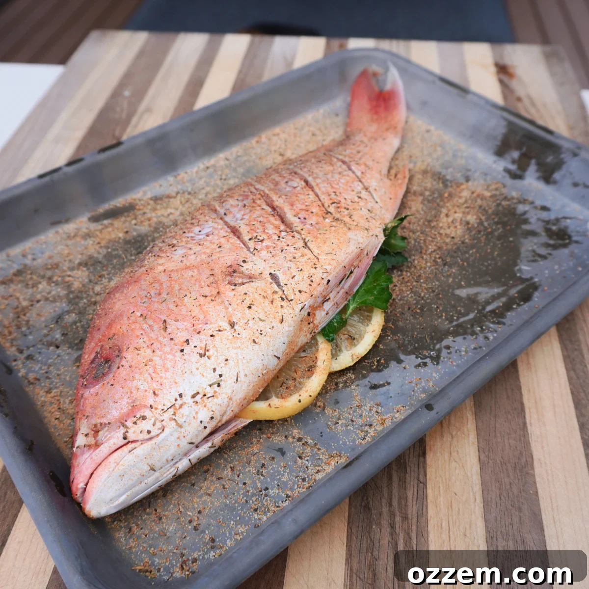 Flame-Kissed Red Snapper 5 Stuffed and seasoned raw red snapper on a metal sheet pan, prepared for grilling.