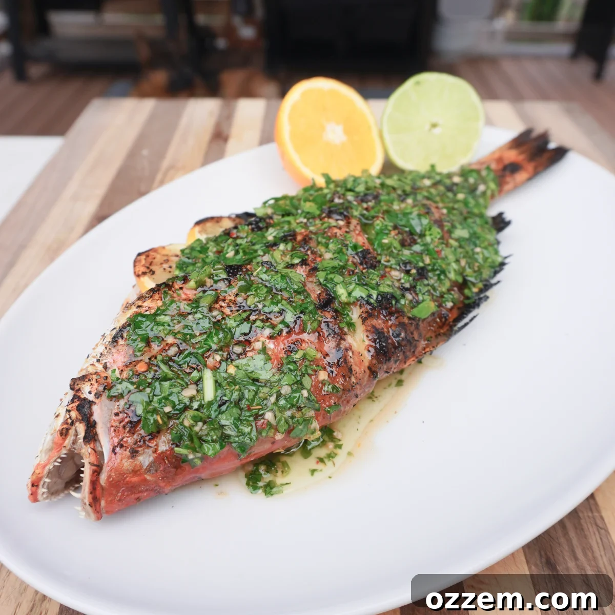 Flame-Kissed Red Snapper 10 Plated grilled red snapper with citrus and chimichurri sauce on a large serving dish.