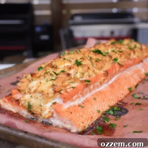 Close-up of a cooked crab stuffed salmon fillet, garnished with fresh herbs and lemon.