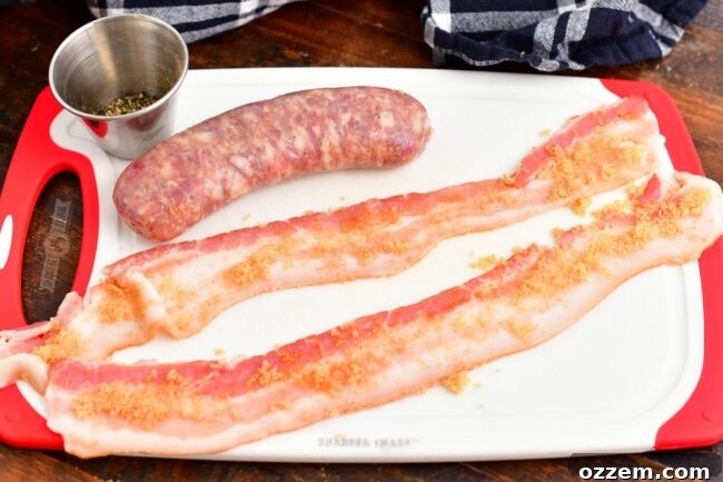 Two sausage links being wrapped with brown sugar-coated bacon strips on a wooden cutting board