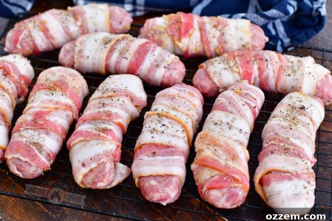 Uncooked bacon-wrapped sausages generously sprinkled with black pepper, ready for the smoker