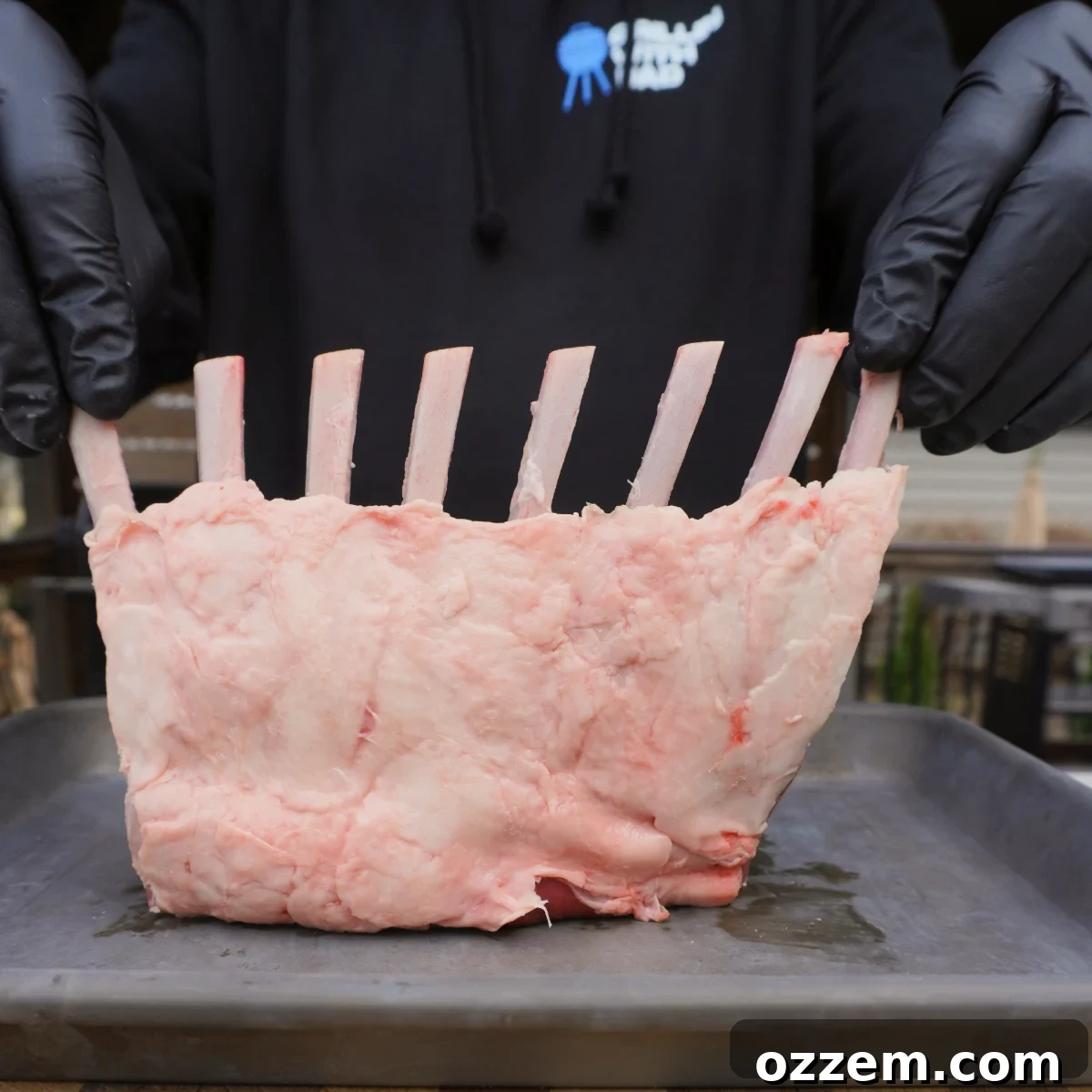 trimmed raw rack of lamb on a metal tray, ready for seasoning.