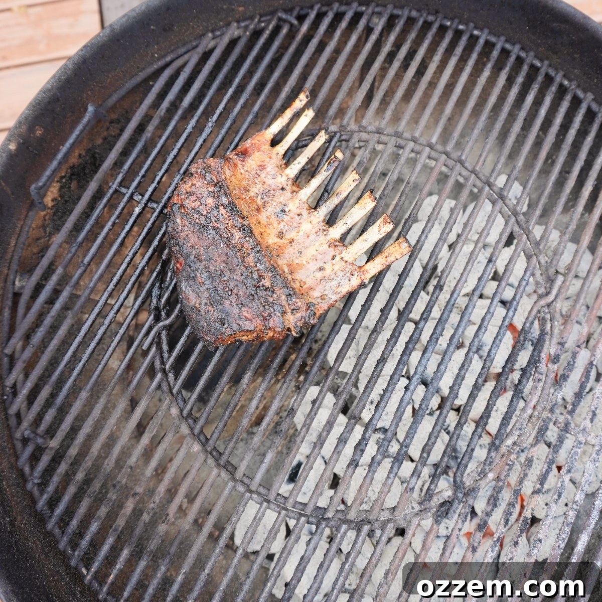 smoking the grilled rack of lamb over indirect heat on a charcoal grill, allowing it to cook gently.