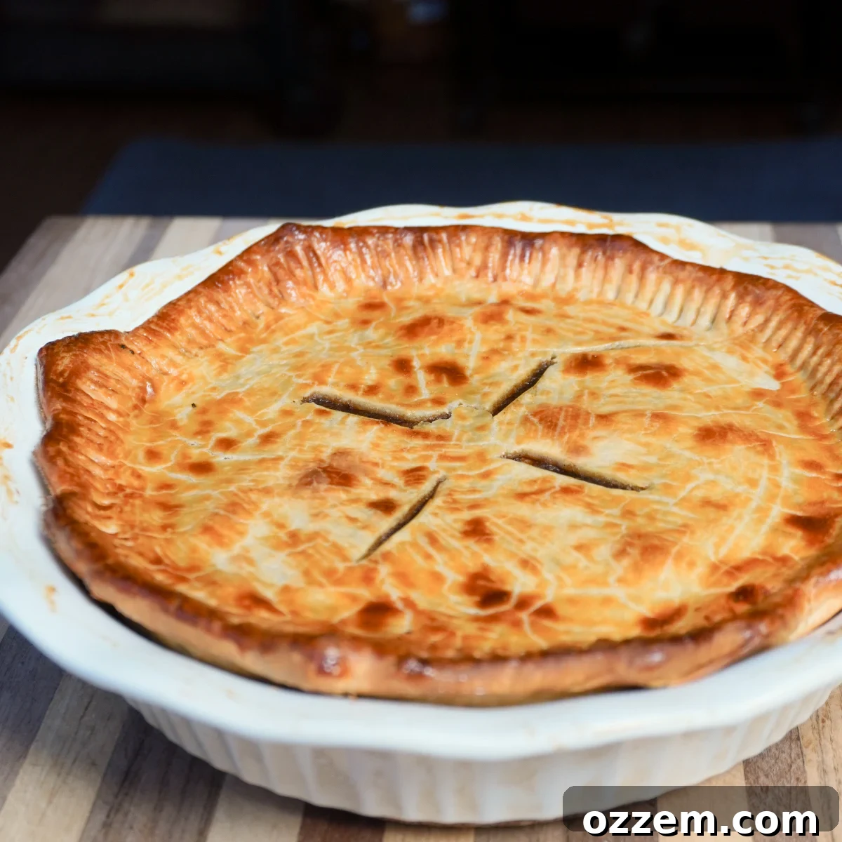 A perfectly baked, golden-brown smoked meat pie in a white ceramic pie dish, ready to be served.